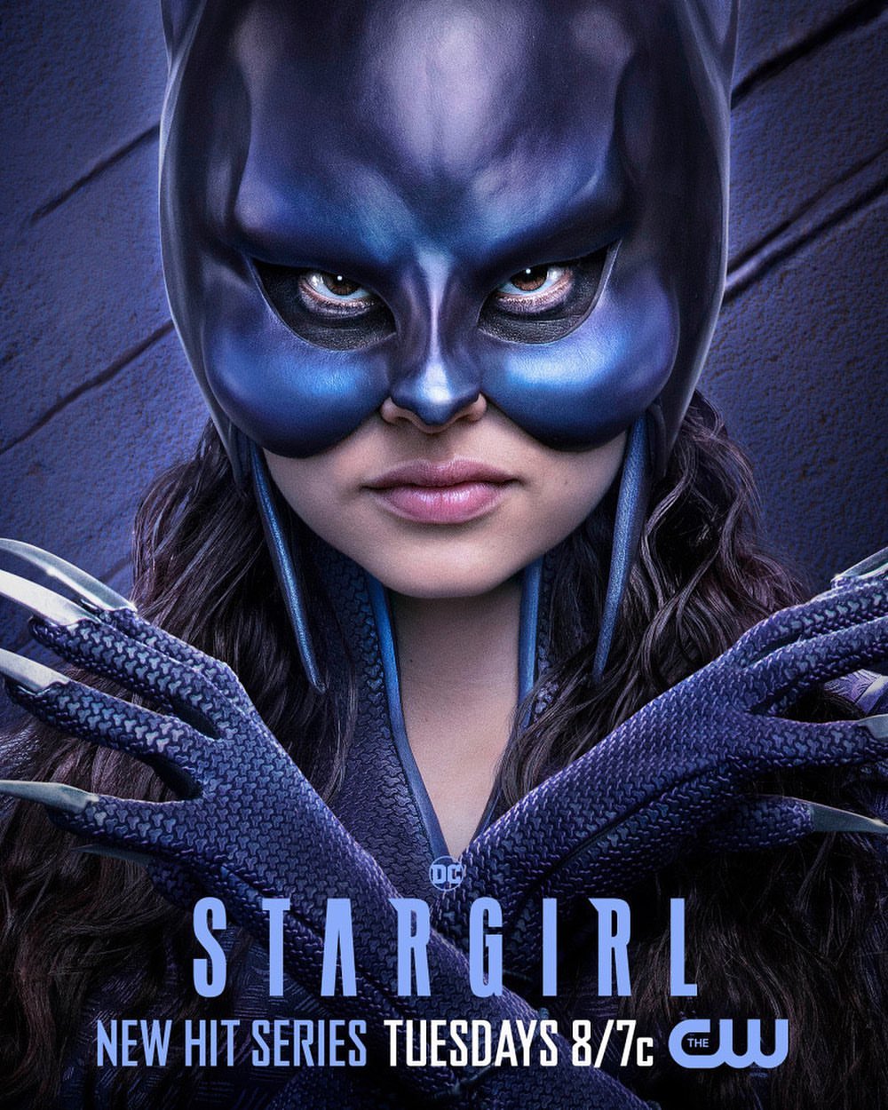 Promotional poster featuring a close-up of a person in a blue superhero mask and suit for the TV series Stargirl, a new hit series.