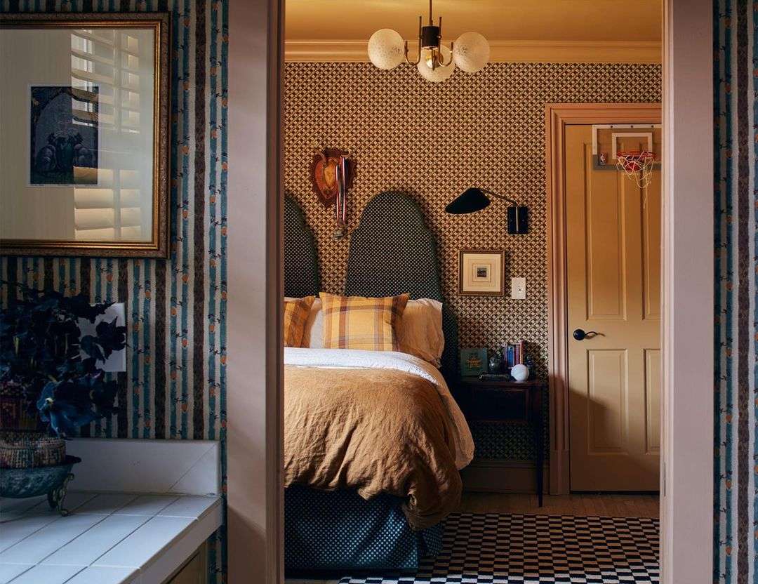 Cozy bedroom interior featuring a bed with patterned headboard, inviting golden comforter, yellow plaid pillows, and decorative accents.