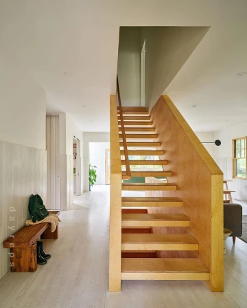 Wooden staircase in a bright residential interior with light walls and white flooring.