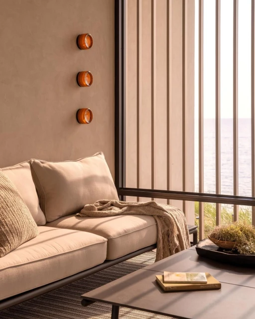 Tan colored living room scene with modern furniture and minimalist amber lighting fixtures illuminating an indoor patio setting.