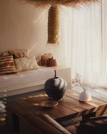 Modern interior design with wooden coffee table, ceramic vases, decorative cushions, and a textured pendant lamp in a neutral color palette.
