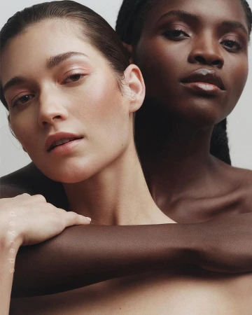 Close-up portrait of two women embracing against a neutral background, photographed by Wolfe + Von.