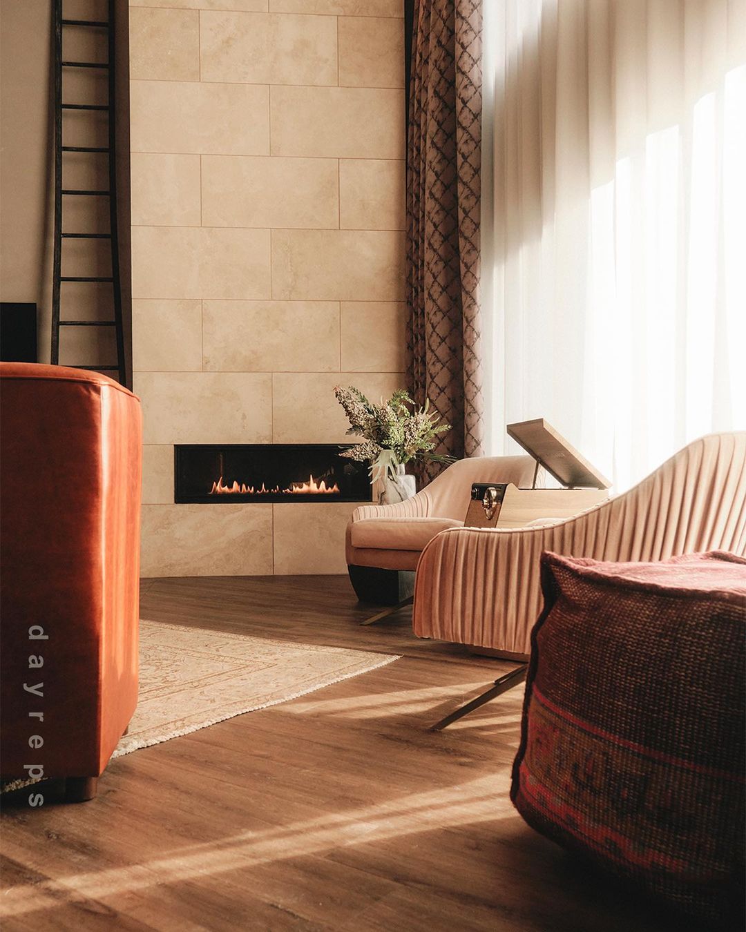 Interior of a living room with a modern fireplace, peach chaise lounge, and unique decor in a home setting with wooden floors.