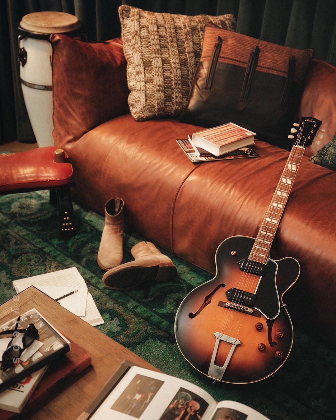 Stylish room interior with a brown leather sofa, guitar, and other decorative objects, creating a cozy and inviting atmosphere.