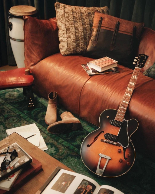 Stylish room interior with a brown leather sofa, guitar, and other decorative objects, creating a cozy and inviting atmosphere.