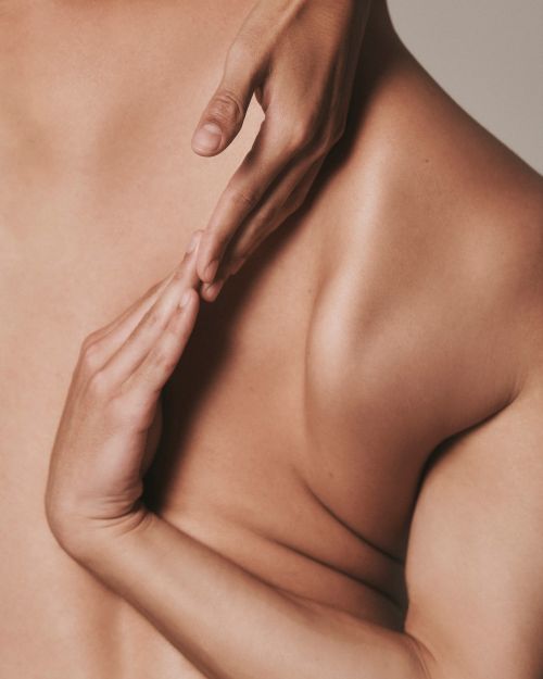 Close-up studio shot of a tan skinned adult and two adult hands. Focus on skin texture and subtle lighting, minimal background.