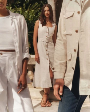 Three fashion models in casual linen outfits pose outdoors. A brunette woman wears a sleeveless dress with button-down details.