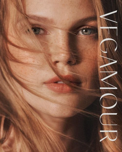 Close-up portrait of a fair-skinned woman with freckles and reddish-blonde hair posing, wearing a natural makeup look with a vertical text overlay.
