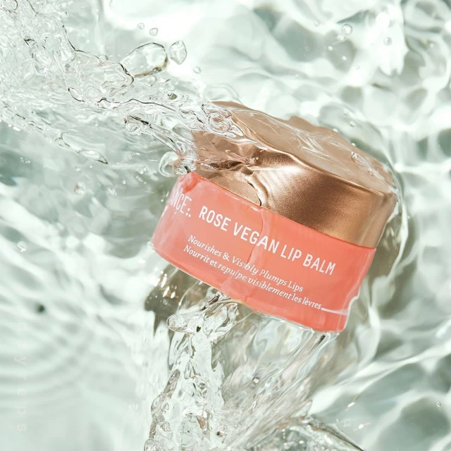 Rose vegan lip balm jar splashing in water, surrounded by clear aqua liquid. Cosmetic product shot with simple watery background.
