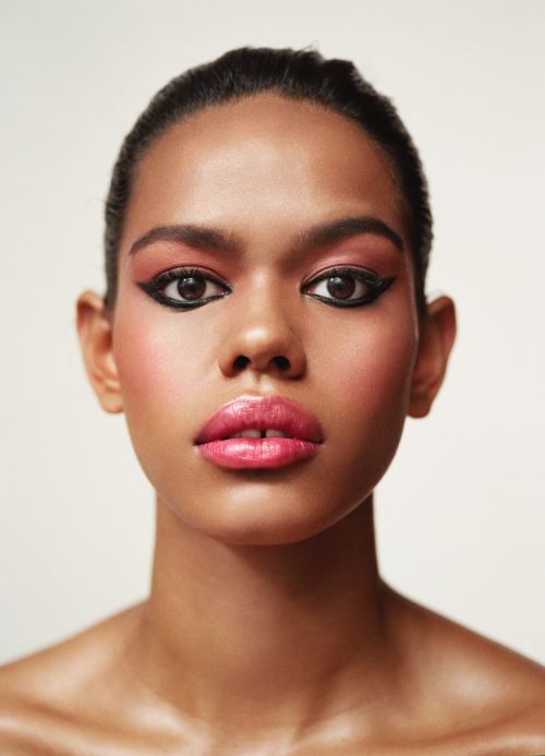 Close-up studio portrait of an adult woman with fair skin and makeup, looking directly at the camera against a neutral background.