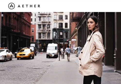 Woman wearing a beige trench coat standing on a cobblestone street with a yellow taxi in the background