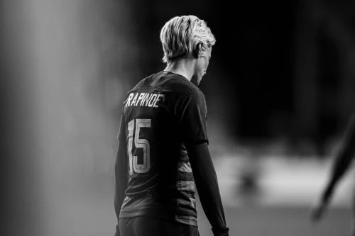 Black and white shot of a female soccer player, Rapinoe, wearing a jersey with the number 15, back view, focusing on athlete and uniform details.