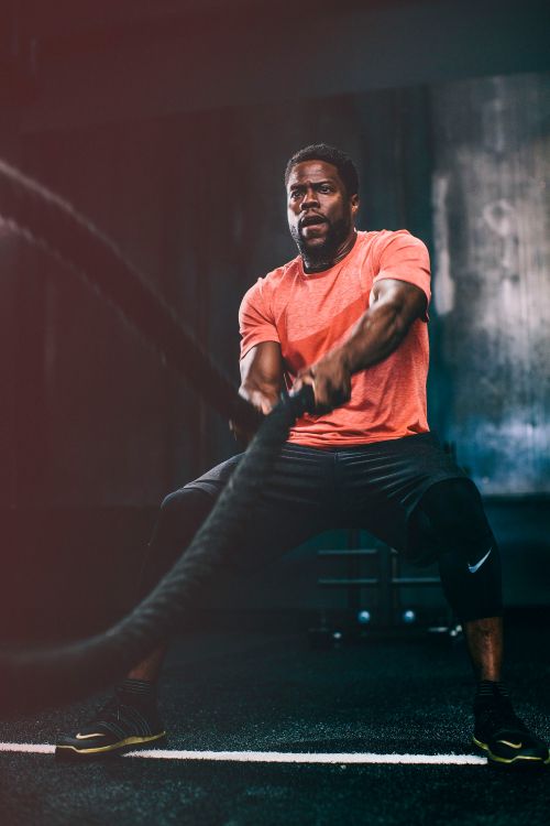 Focused adult male intensely works out with battle ropes in a fitness center, showcasing strength and determination during an exercise routine.