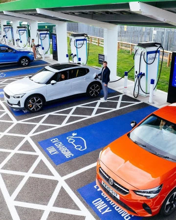 Multiple electric vehicles charging at a modern outdoor charging station, emphasizing sustainable transportation and innovative automotive technology.