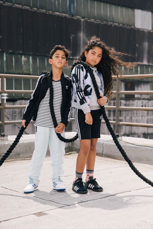 Two children holding thick black climbing ropes on a concrete rooftop by photographer Nick Laham