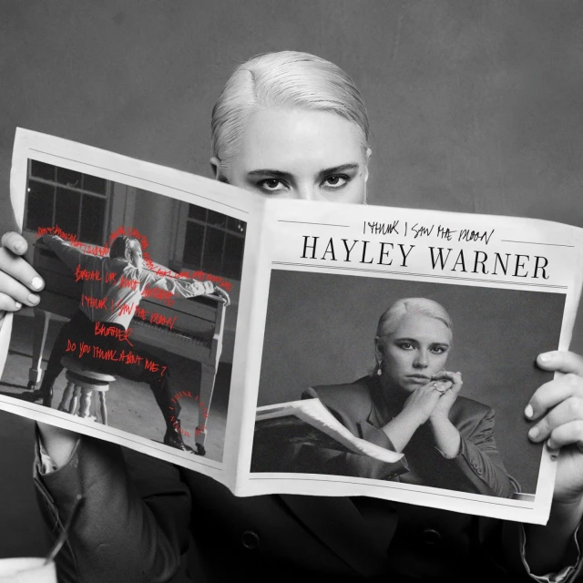 Black and white portrait of singer Hayley Warner holding a newspaper featuring her images and the words 'I Think I Saw the Moon'.