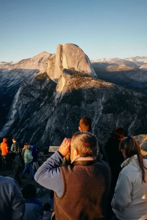 Scenic view of Half Dome in Yosemite National Park with a group of people observing the landscape under a clear blue sky.