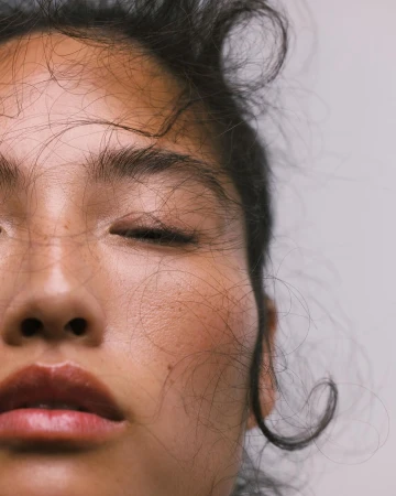 Close-up portrait of a woman with loose hair strands across her face, captured by photographer Ali Mitton.