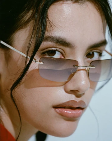 Close-up portrait of a woman wearing rimless gradient sunglasses by photographer Ali Mitton.
