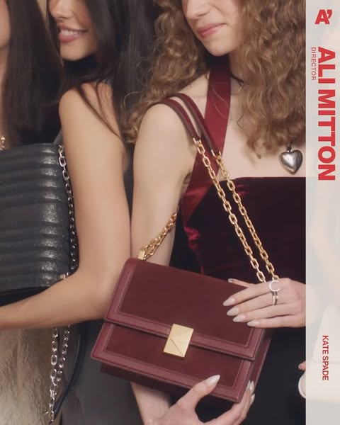 Three women showcase Kate Spade handbags in a close-up shot. One wears a burgundy velvet top and gold jewelry, against a blurred background.
