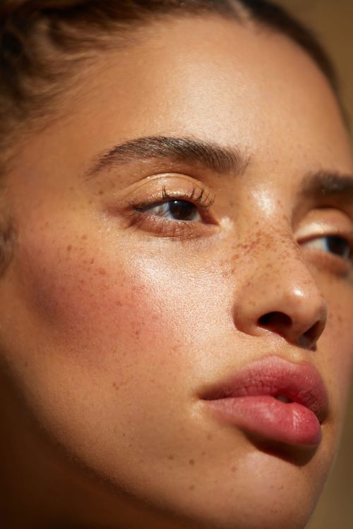 Close up portrait of a young woman with freckles, dewy skin, and glowing natural light photographed by Ali Mitton.