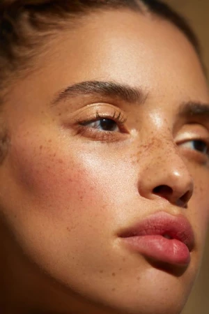Close up portrait of a young woman with freckles, dewy skin, and glowing natural light photographed by Ali Mitton.