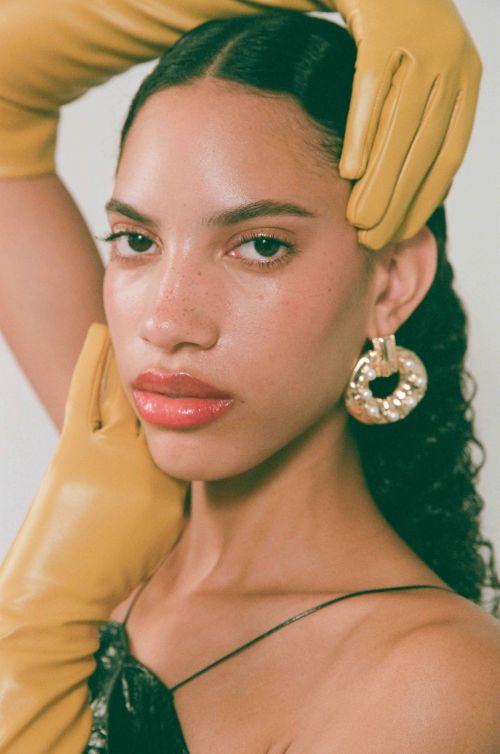 Portrait of a woman wearing mustard yellow leather gloves and large pearl hoop earrings by photographer Ali Mitton
