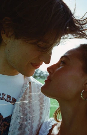 Close-up portrait of a young man and woman gazing affectionately at each other outdoors by Ali Mitton.
