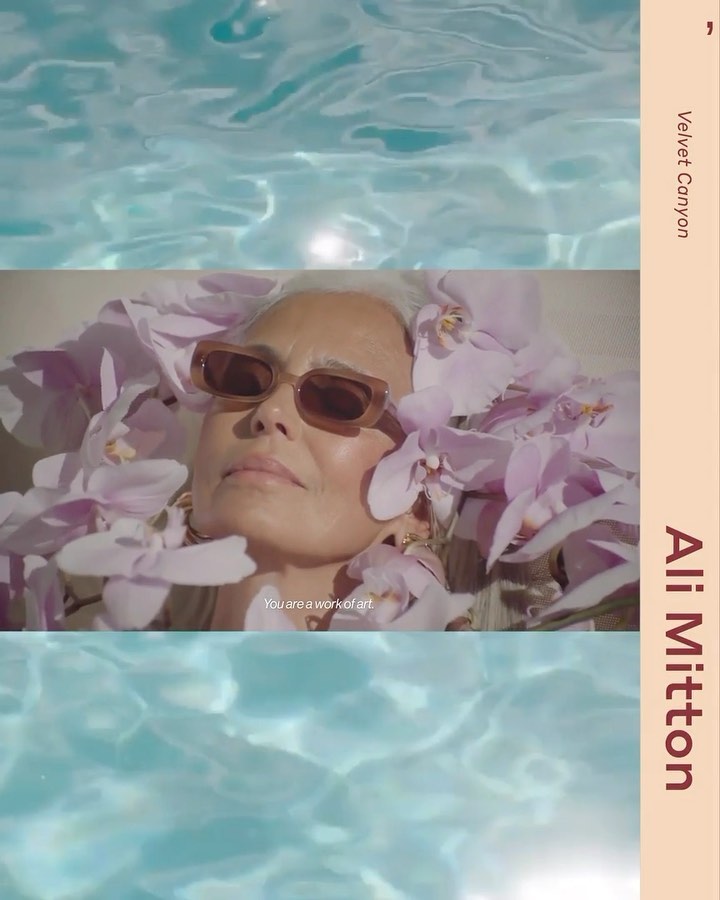 Older woman with sunglasses laying in pink orchids, under water surface, for beauty campaign by Ali Milton & Velvet Canyon.
