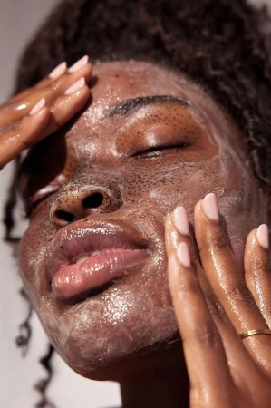 Close-up of an African American woman with facial scrub, gently massaging her face. Focus on skincare and beauty, showcasing natural skin.