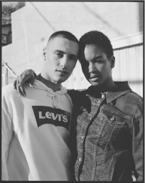 Black and white portrait of a man and a woman posing together outdoors against a building exterior wall.