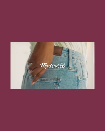 Close-up of an adult person wearing light wash jeans with their hand in the back pocket, featuring the Madewell brand label.