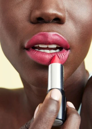 Close-up of a person applying vibrant pink lipstick to their lips with a silver tube