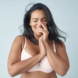 Smiling woman in light pink bra with dark hair against a pale blue background