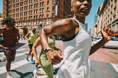 Group of runners jogging across a city street with historic brick buildings in the background shot by Jeff Vallee.
