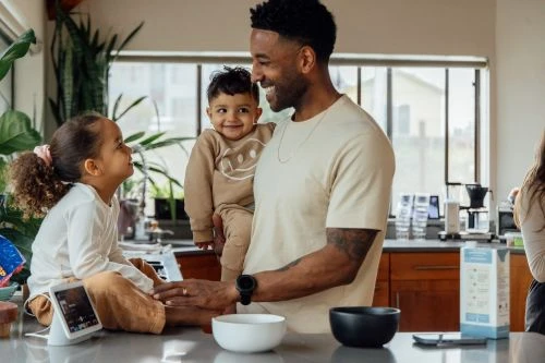 Father and two young children in a kitchen setting, captured in a medium shot showcasing a casual and heartwarming family scene.
