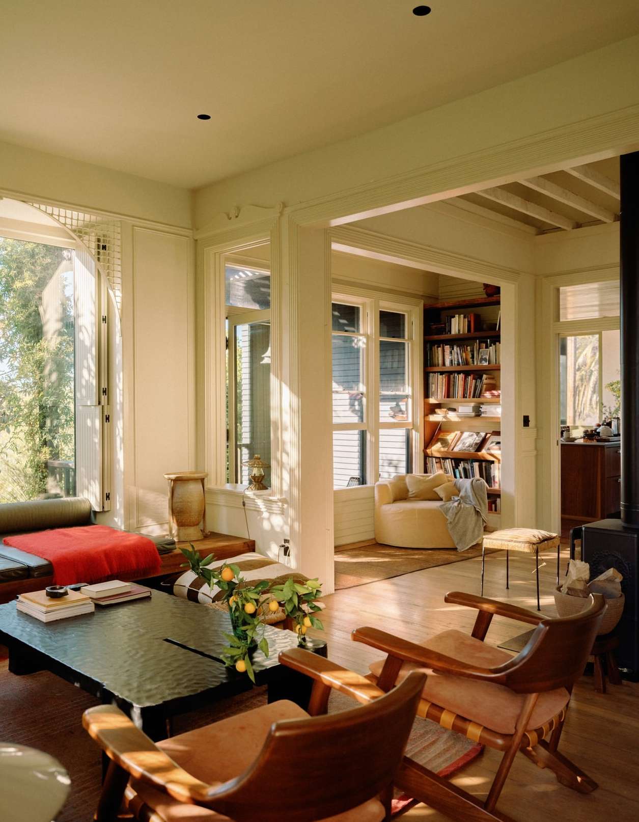 Living room interior featuring a dark wood coffee table, tan armchairs, and bright window light, creating a cozy and inviting atmosphere.