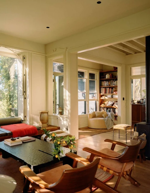 Living room interior featuring a dark wood coffee table, tan armchairs, and bright window light, creating a cozy and inviting atmosphere.