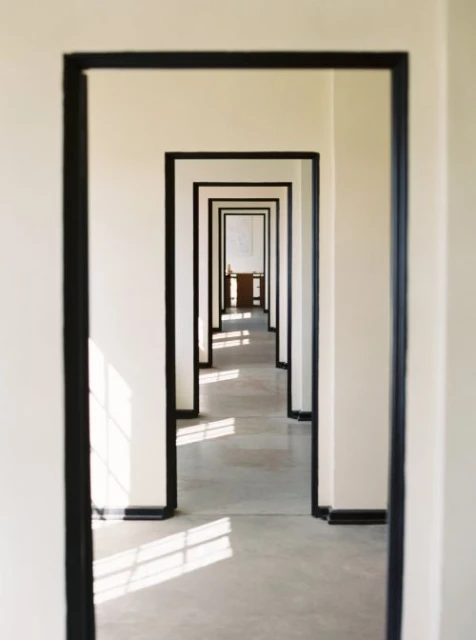 Hallway perspective with repeated doorways receding into the distance, casting geometric light patterns on the floor.