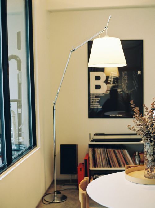 Interior view features an adjustable floor lamp with a white shade, vinyl records, and a poster with the letter B on a wall.