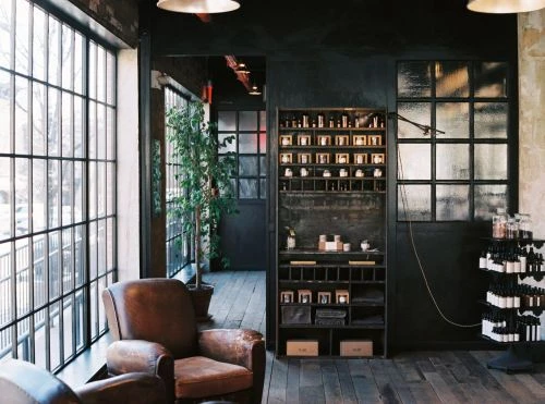 Interior view of a room with two leather armchairs near a large window, a display case, and hardwood floors, creating a cozy atmosphere.