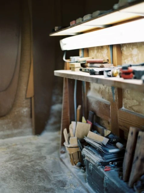 Woodworking shop interior with workbench and tools under bright lights, featuring various implements for craft projects.