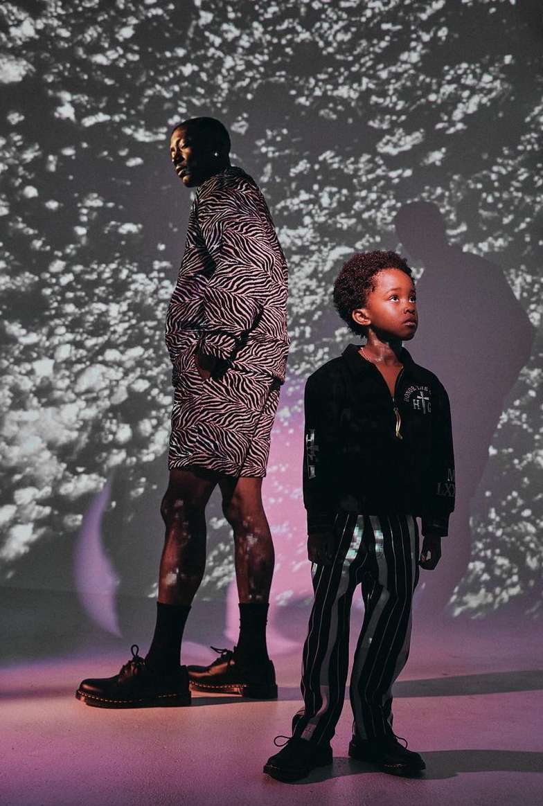 Fashion shot of an adult and child wearing matching patterned zebra-print outfits in front of a mottled background with soft studio lighting.