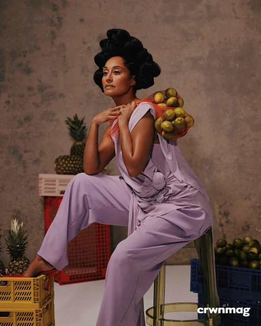 Stylish portrait of a woman in a lavender outfit, seated and holding lemons with pineapples, set against a textured backdrop.