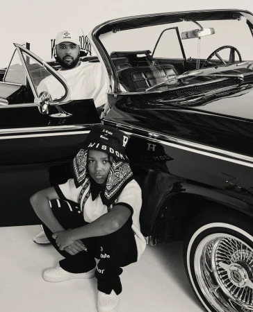Monochrome portrait by Mark Clennon featuring a man seated in a vintage convertible and a child crouching in the foreground.