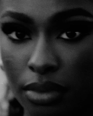 Close-up black and white portrait of a Black woman with dramatic eye makeup shot by Mark Clennon