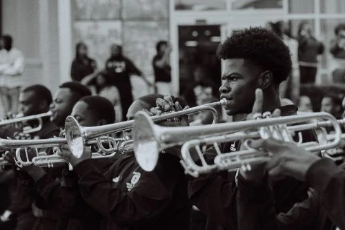 Monochrome shot of a marching band performing outdoors, showcasing brass instruments and uniformed musicians in a public space.