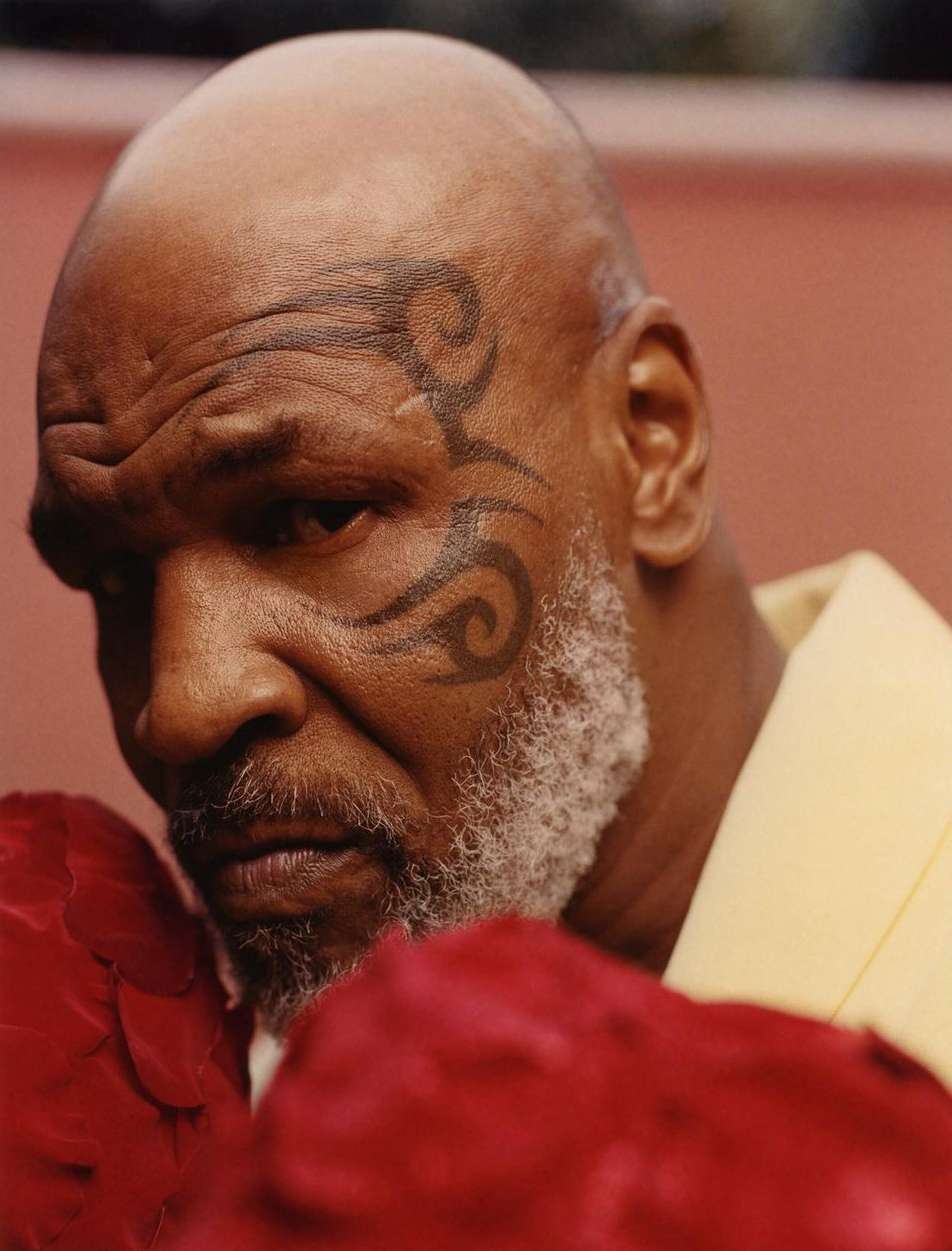 Close-up studio portrait of bald adult male with face tattoo wearing boxing gloves. Focus on the man's face and upper chest.
