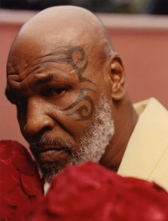 Close-up studio portrait of bald adult male with face tattoo wearing boxing gloves. Focus on the man's face and upper chest.