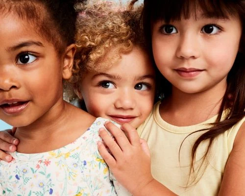 Close-up portrait of three young children together, photographed by Priscilla Gragg.